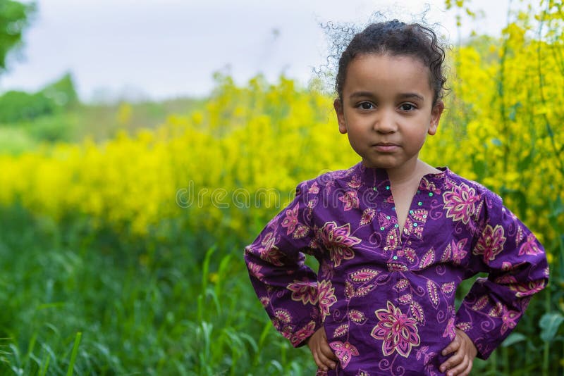 Cheeky Mixed Race African American Girl Child in Field of Yellow Flowers royaltyfria bilder Cheeky Mixed Race African American Girl Child in Field of Yellow Flowers royaltyfria bilder