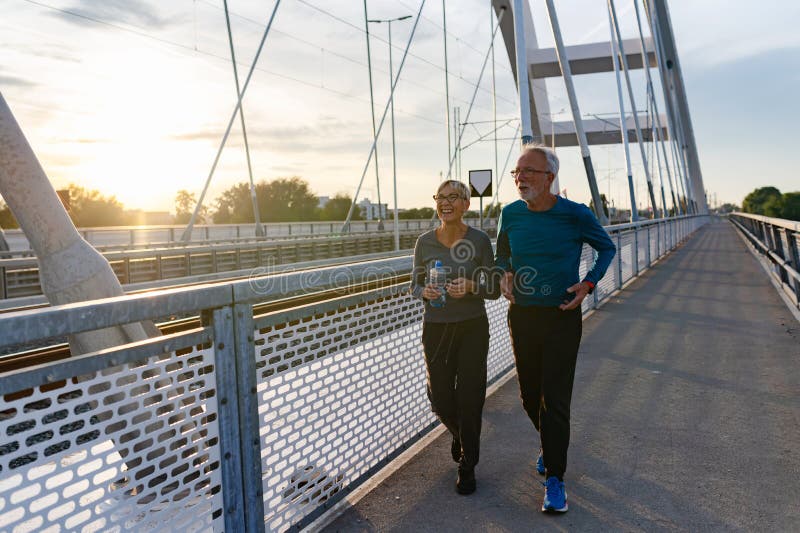 Cheerful Active Senior Couple Jogging Together Outdoors Along the River ...