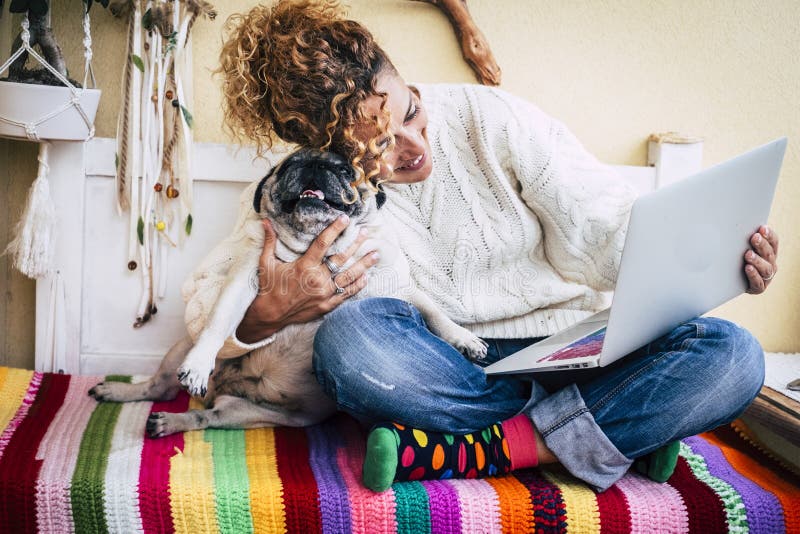 Cheerful adult caucasian. woman work happy with tablet computer hugging her best friend old funny dog pug - coloured image for