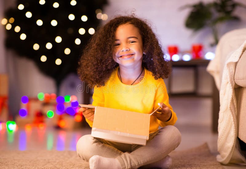 Cheerful afro-flicka som njuter av sin lysande julklapp royaltyfri bild