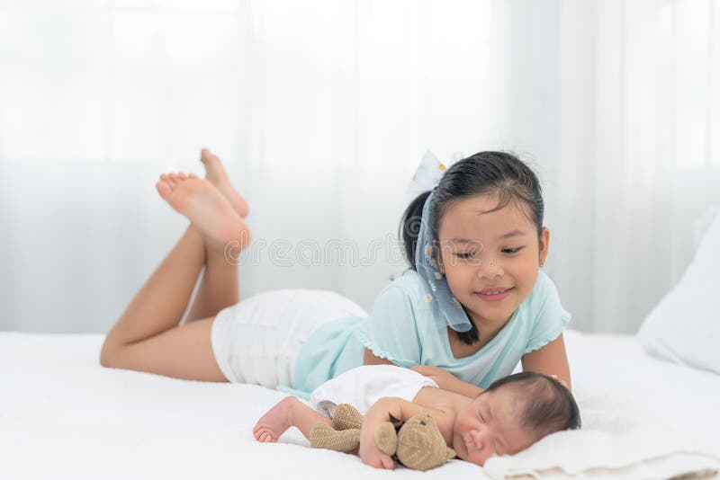 Cheerful Asian Girl Happy Playing Around Her Newborn Brother, while ...