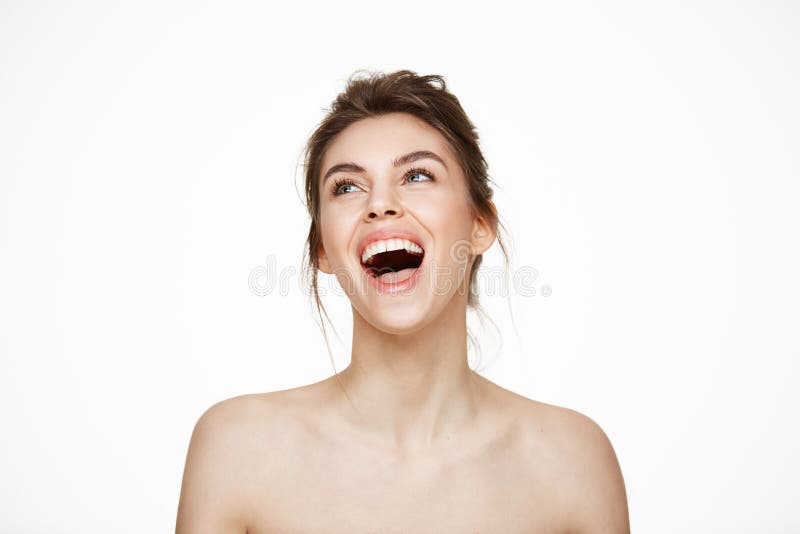 Cheerful beautiful naked girl rejoicing smiling laughing over white background. Facial treatment. Beauty and health.