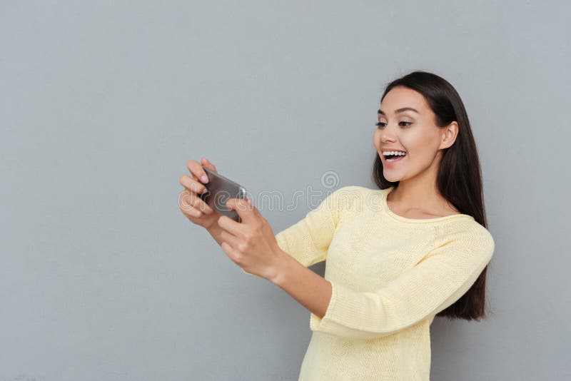 Cheerful beautiful young woman playing video games on mobile phone stock photos Cheerful beautiful young woman playing video games on mobile phone stock photos