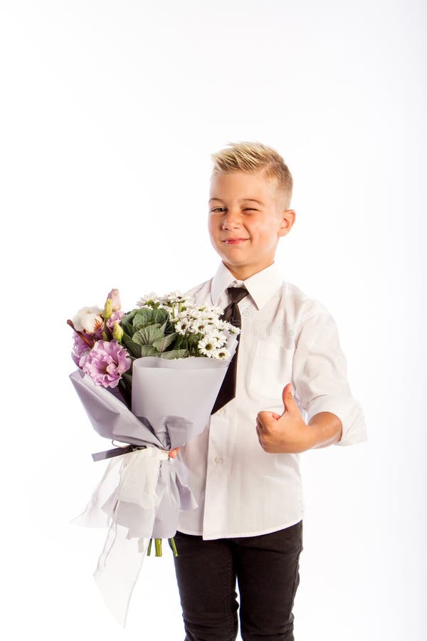 Cheerful blond fashionable boy gives bouquet and thumbs up on white studio background, delivery flowers, Spring Womens Day