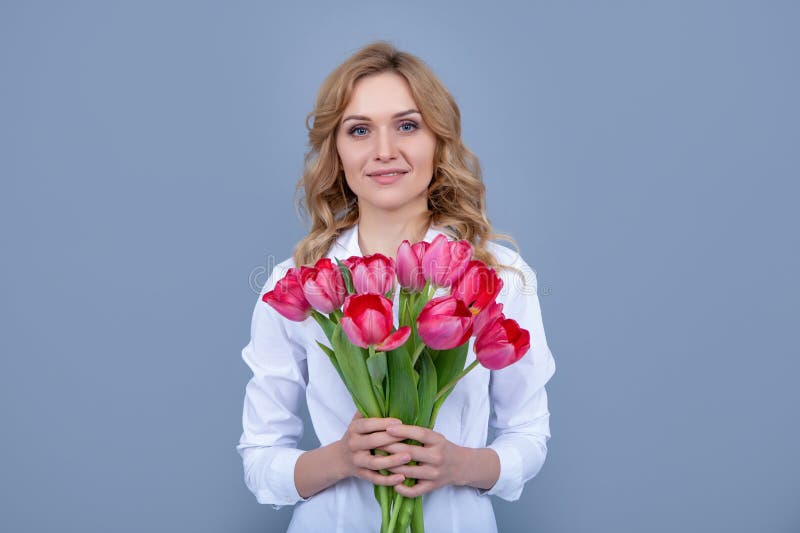 cheerful blond woman with spring tulip flowers on grey background stock photography