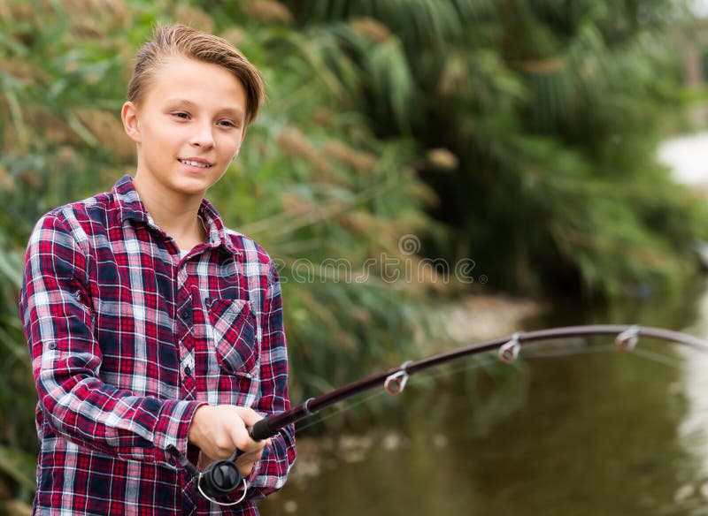 Cheerful boy casting line for fishing on lake royalty free stock images