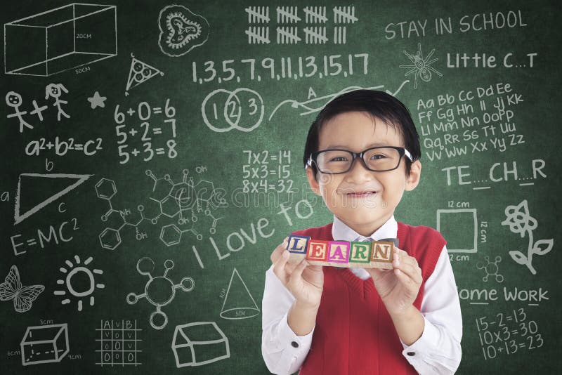 Cheerful boy student holding LEARN block royalty free stock photo