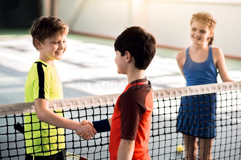 Cheerful boys shaking hands before playing tennis