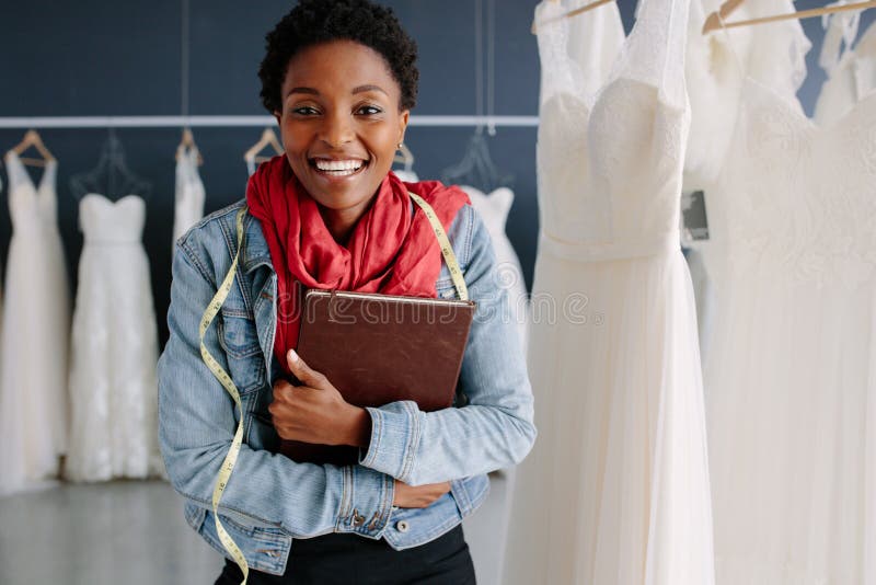 Cheerful bridal store owner standing in her boutique with a diary. Female wedding fashion designer in a bridal boutique.