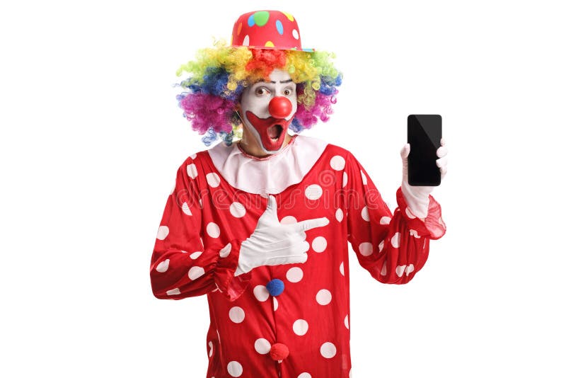 Cheerful clown holding a mobile phone and pointing at it royalty free stock photography