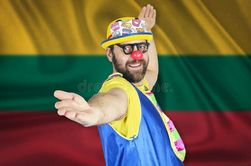A cheerful clown stands in a welcoming pose against the background of the flag of Lithuania royalty free stock images