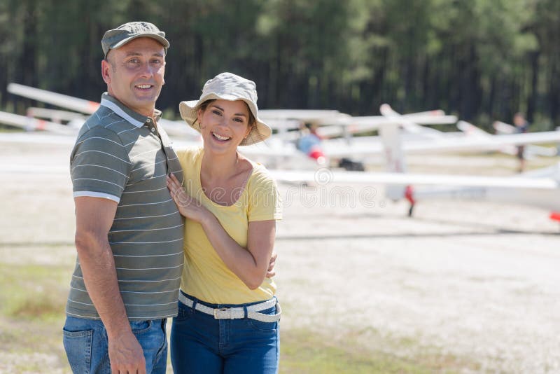 Cheerful couple hugging and laughing near private plane