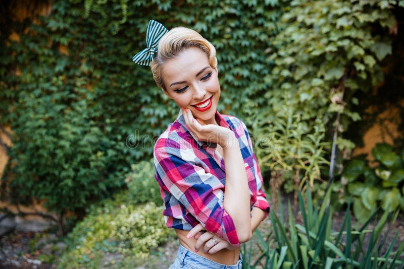 Cheerful cute pinup girl in plaid shirt standing and smiling