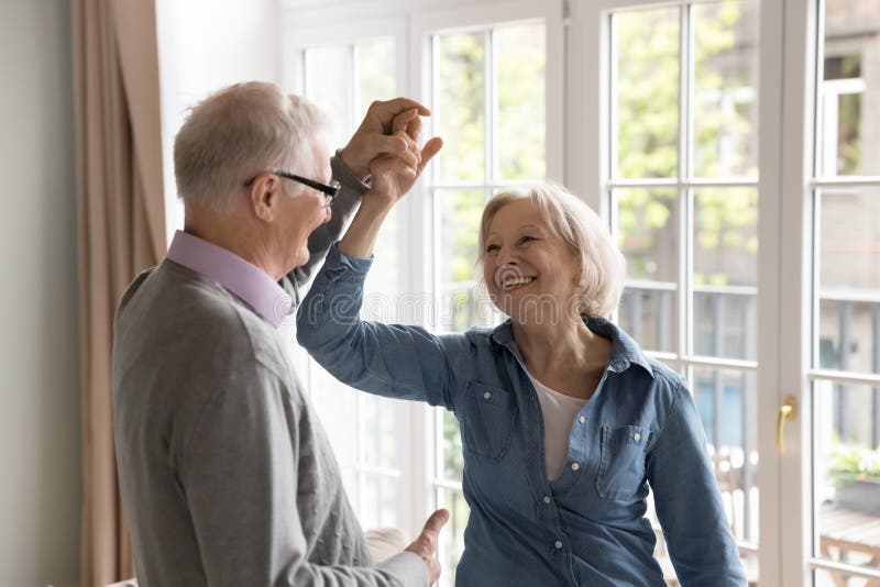 Cheerful Elderly Energetic Couple In Love Dancing Together At Home