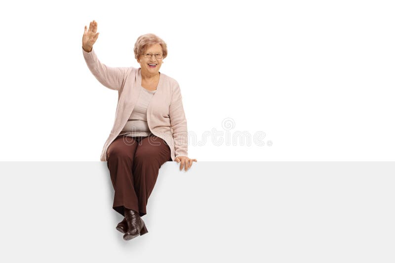 Cheerful elderly woman sitting on a panel and waving