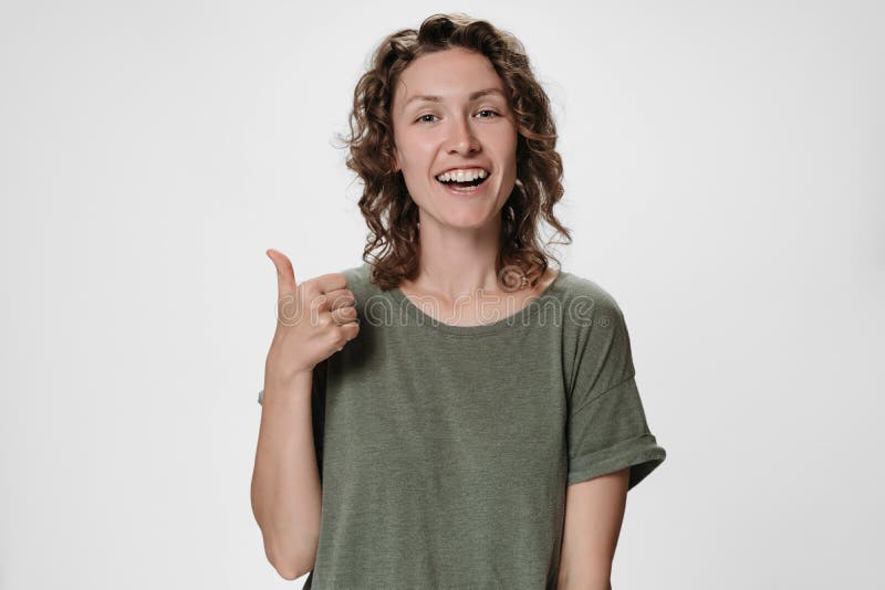 Cheerful enthusiastic pleased young caucasian curly woman showing thumbs up gesture royalty free stock photography Cheerful enthusiastic pleased young caucasian curly woman showing thumbs up gesture royalty free stock photography