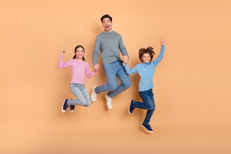 Cheerful family jumping together in colorful clothing on a beige background showcasing joy, bonding stock photos