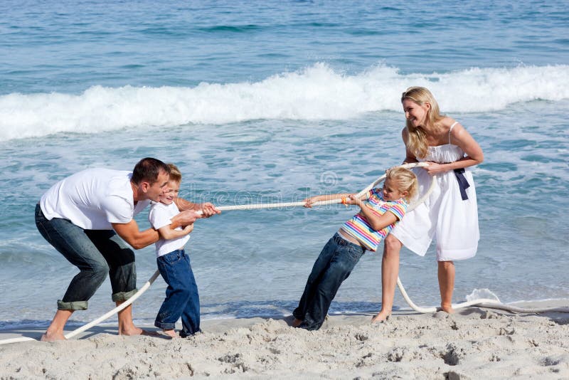 Cheerful family playing tug of war at the beach
