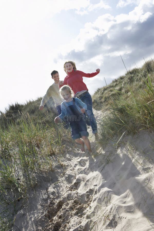 Cheerful Family Running Through Sand Dunes
