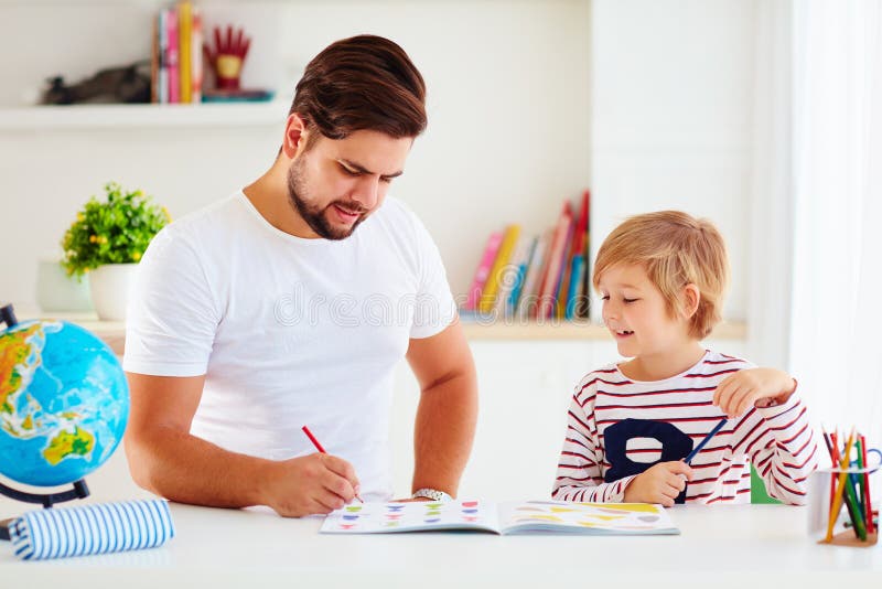 Father and son having fun together at the desk, coloring the book