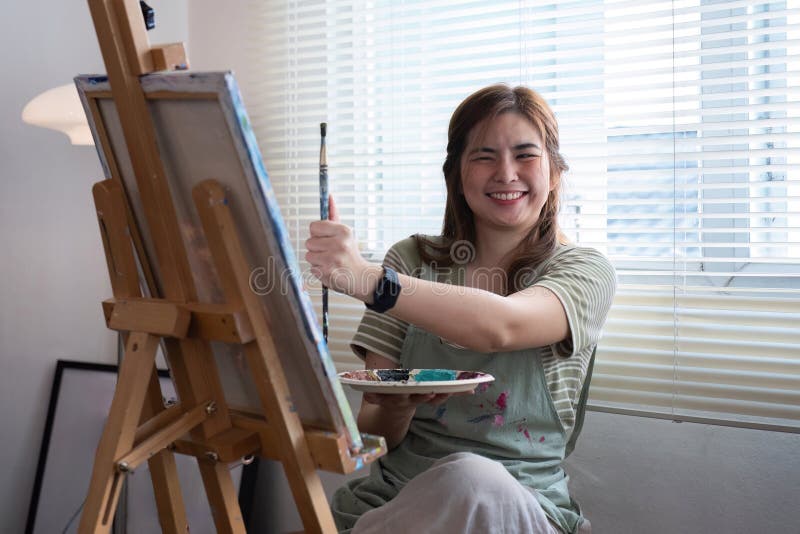 Talented Female Artist Joyfully Painting on Canvas in Bright Studio with Natural Light royalty free stock images