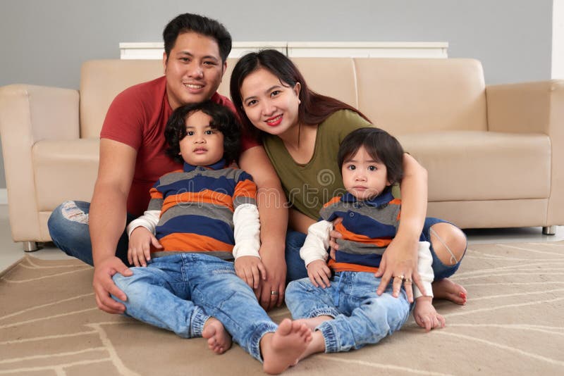 Cheerful Filipino family sitting on the floor in living room. Cheerful Filipino family sitting on the floor in living room