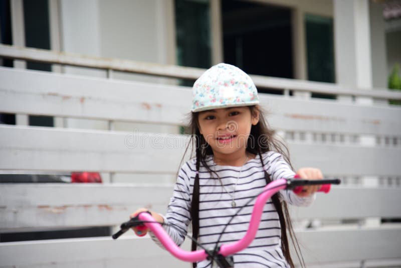 Cheerful girl ride bicycle on a driveway outside on sport day. Little cute girls riding bikes on the road. Cyclist fun happy