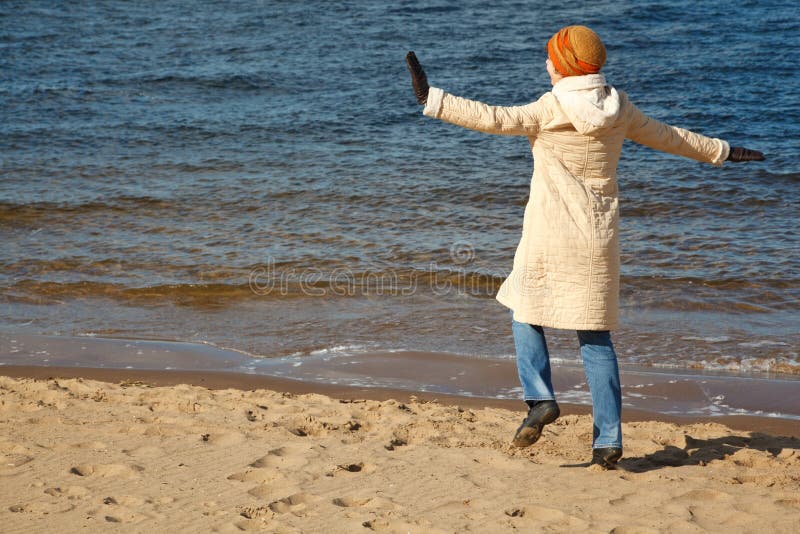 Cheerful girl walks on beach in solar autumn day