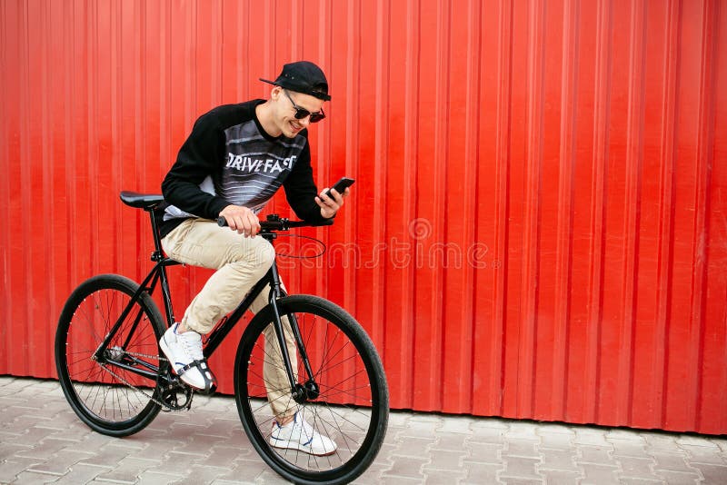 Cheerful Guy Sitting on Bike and Using a Smartphone Stock Image - Cheerful Guy Sitting Bike Using Smartphone OutDoor Photo Stylish Man Bicycle Looking Phone Screen Smiling OutDoors 155294329