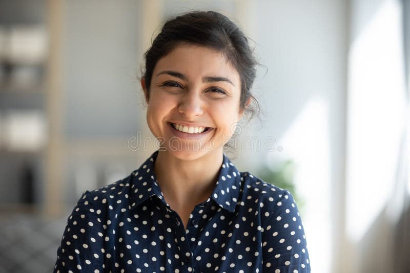 Cheerful indian tjej på hemkontoret som tittar på kameran