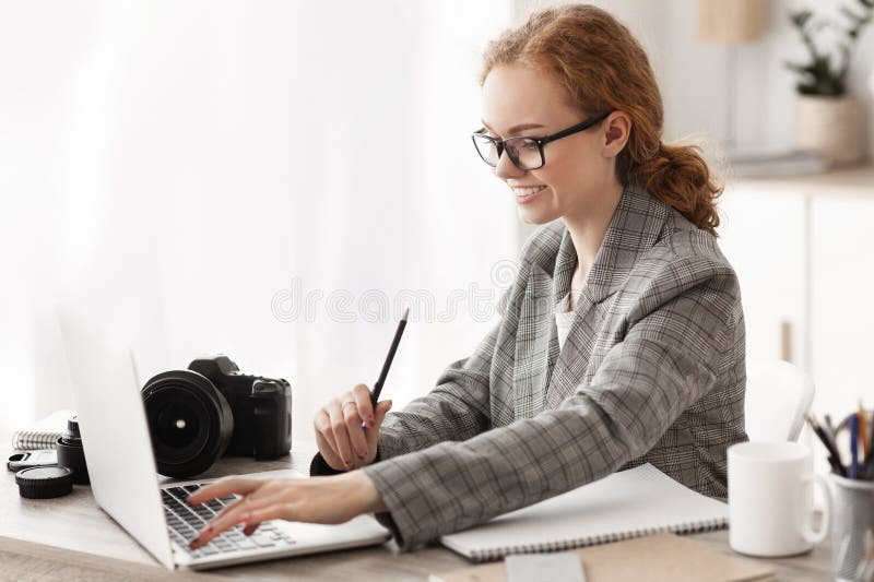 Cheerful journalist working in office on laptop stock photos