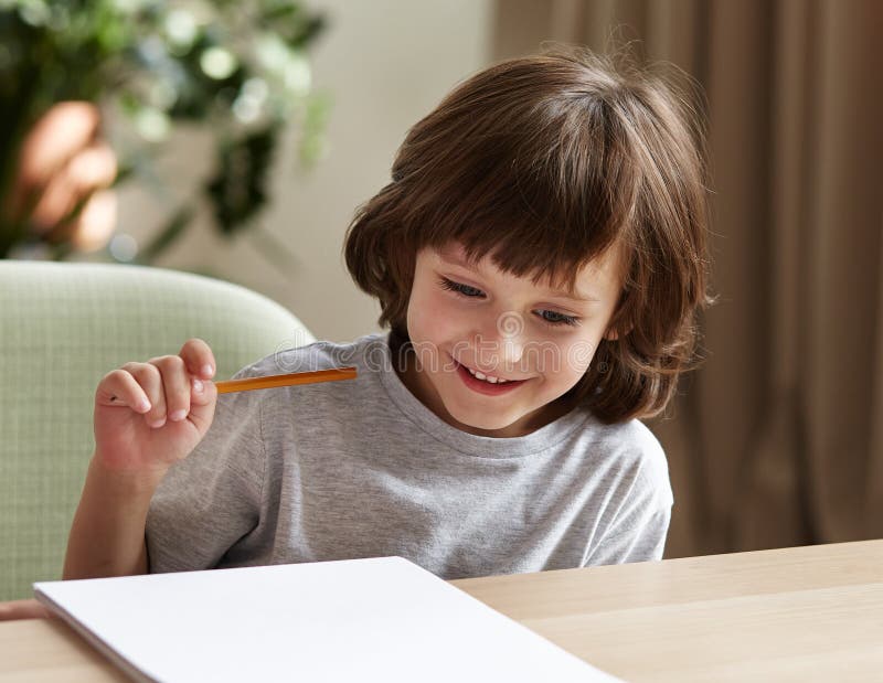 A cheerful little boy is solving math tasks and finding answers to tests to prepare for school. royalty free stock photos