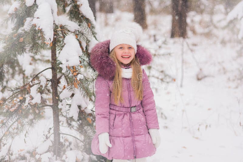 Cheerful Little Girl is Standing at the Snow-covered Trees in the Woods ...