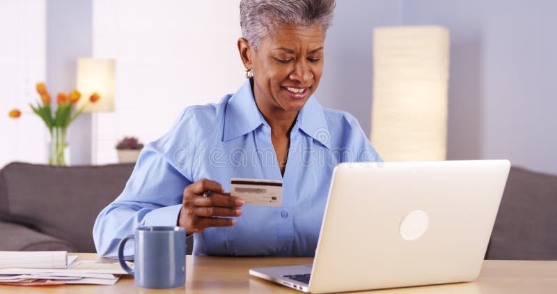 Cheerful Mature African woman buying things online royalty free stock images Cheerful Mature African woman buying things online royalty free stock images