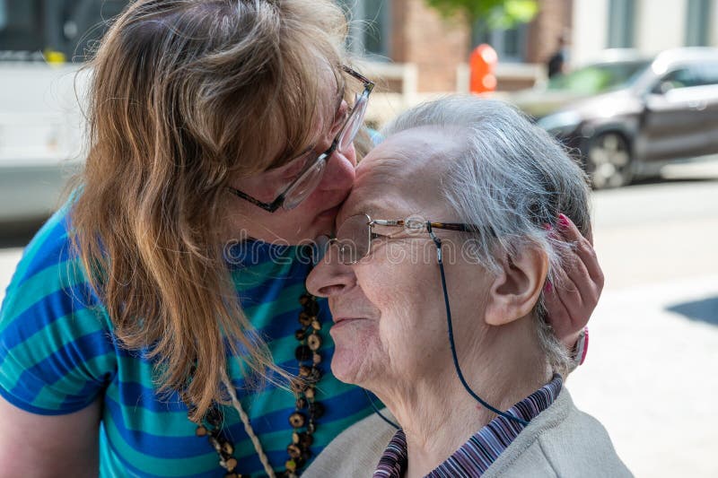 Cheerful moment between an 83 year old senior woman kissing her 39 year old daughter with the Down Syndrome