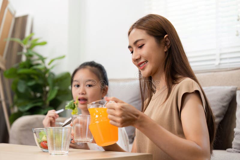 Wellness in daily routines: Mother and daughter enjoying juice and salad stock photo
