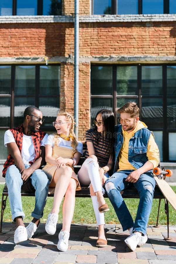 Cheerful multicultural couples resting on bench together royalty free stock image