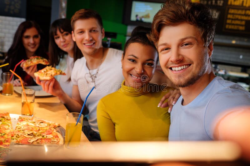 Cheerful multiracial friends taking selfie in pizzeria. stock photos Cheerful multiracial friends taking selfie in pizzeria. stock photos