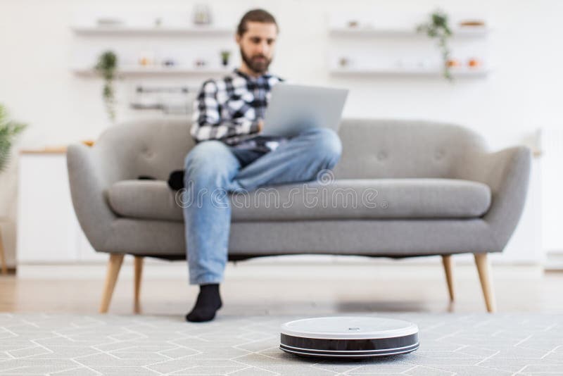 Cheerful owner programming home gadget via remote control while focusing on work stock image