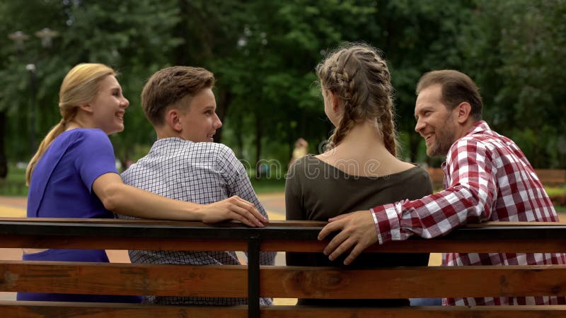 Cheerful parents and their teenage children planning weekend on bench in park royalty free stock images Cheerful parents and their teenage children planning weekend on bench in park royalty free stock images