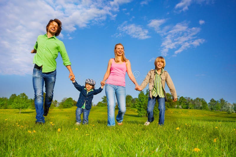 Cheerful parents holding hands and walking with boys in park in summer. Cheerful parents holding hands and walking with boys in park in summer