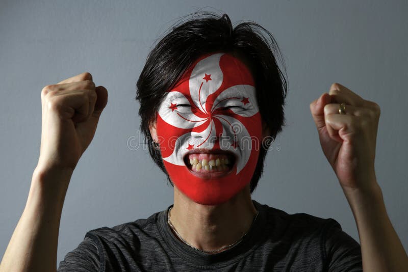 Cheerful portrait of a man with the flag of the Hong kong painted on his face on grey background. The concept of sport. royalty free stock photo Cheerful portrait of a man with the flag of the Hong kong painted on his face on grey background. The concept of sport. royalty free stock photo