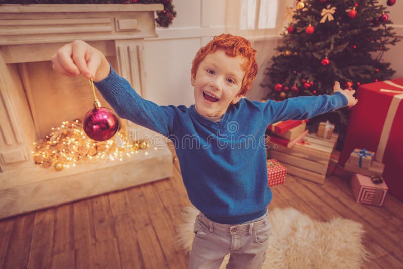 Cheerful red-haired boy posing with a Christmas ball royalty free stock image Cheerful red-haired boy posing with a Christmas ball royalty free stock image