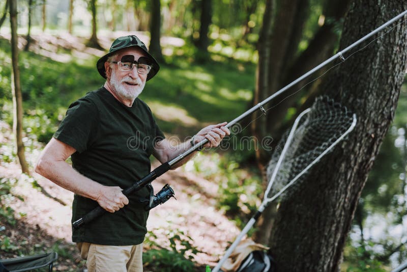 Cheerful retired man enjoying fishing activity with pleasure royalty free stock photo Cheerful retired man enjoying fishing activity with pleasure royalty free stock photo