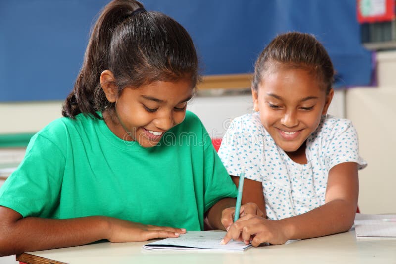 Cheerful school girls in class learning together