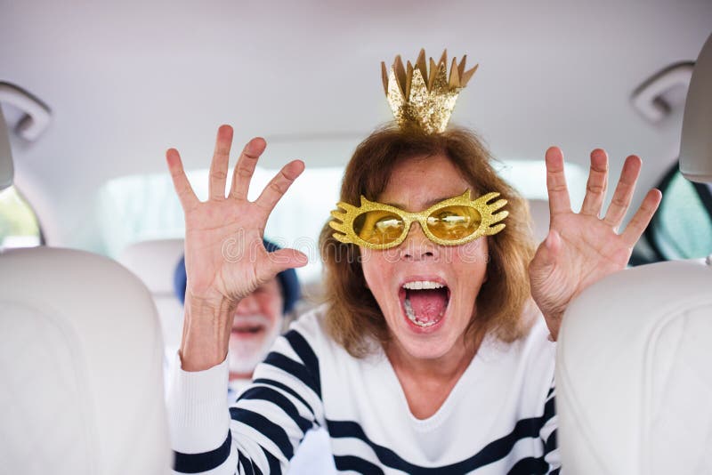Cheerful senior couple with party accessories sitting in car, having fun. royalty free stock photos Cheerful senior couple with party accessories sitting in car, having fun. royalty free stock photos