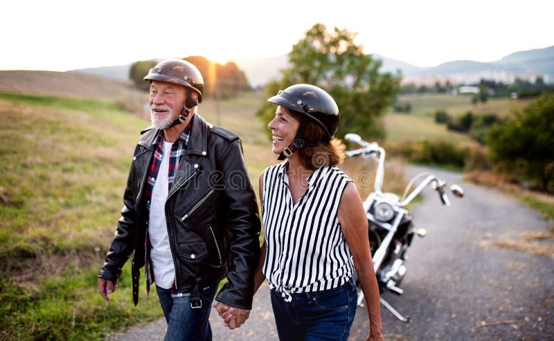 A cheerful senior couple travellers with motorbike in countryside. stock image A cheerful senior couple travellers with motorbike in countryside. stock image