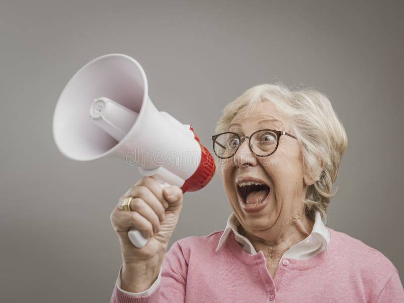 Cheerful senior lady shouting into a megaphone royalty free stock photo Cheerful senior lady shouting into a megaphone royalty free stock photo