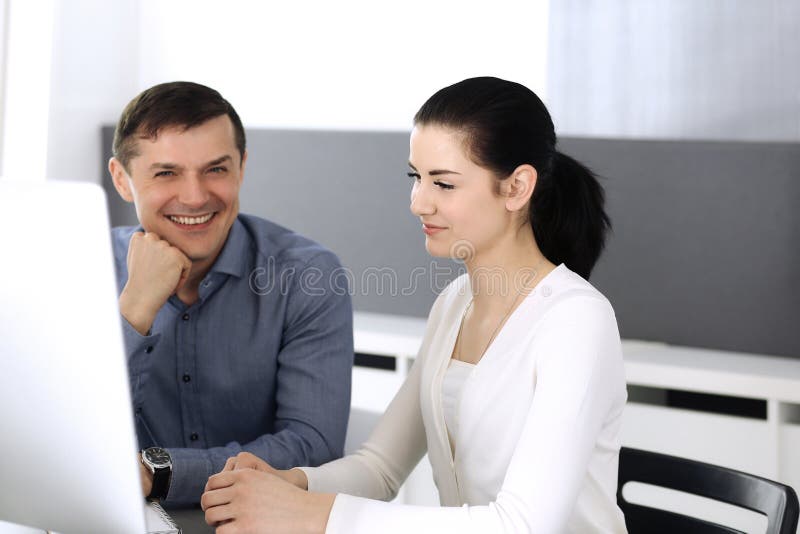 Cheerful smiling businessman and woman working with computer in modern office. Headshot at meeting or workplace royalty free stock image