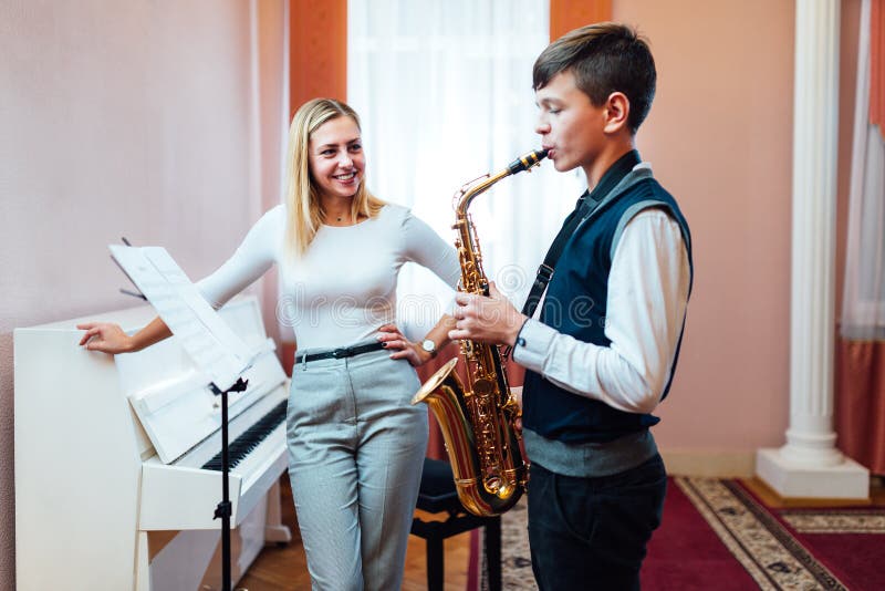 Cheerful Teacher with Student Boy Learning Saxophone Lessons at School